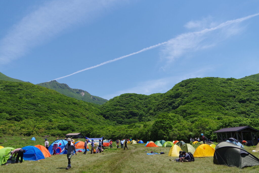 青空のもと大勢のテントで賑わう坊がつる