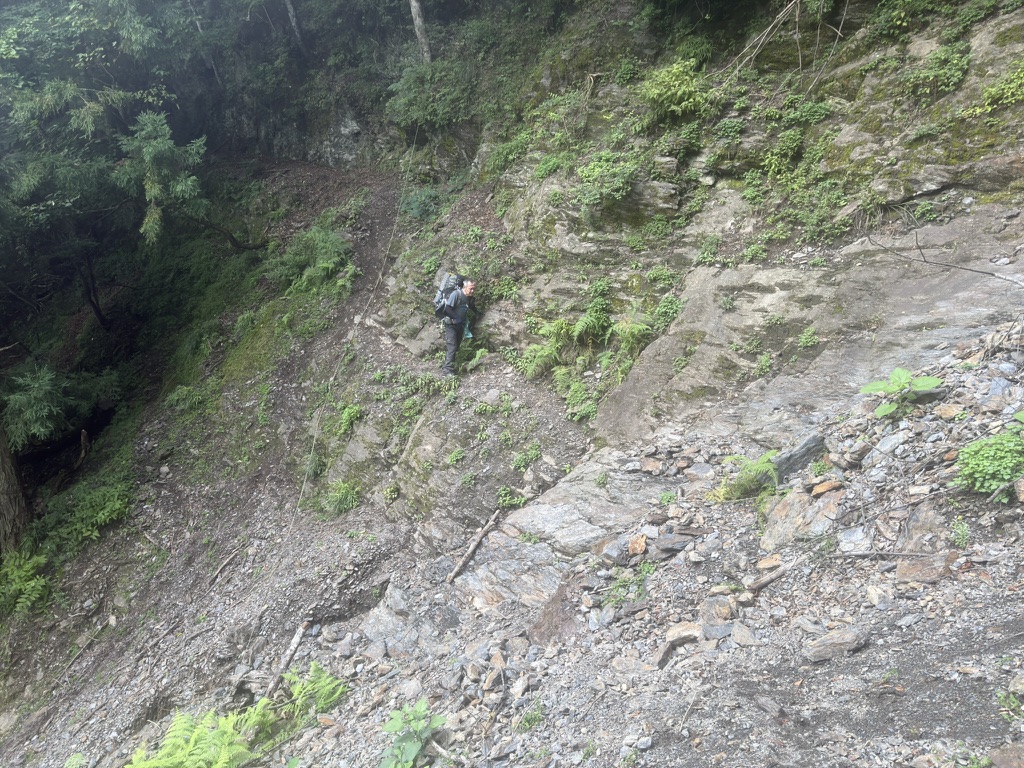 崩落地トラバースするTさん（広河原から老平登山口の間で撮影）