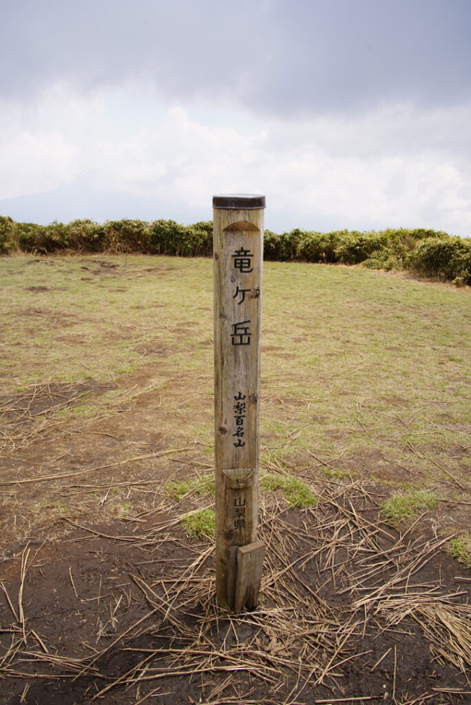 広い山頂にある山梨百名山の標柱（竜ヶ岳山頂で撮影）