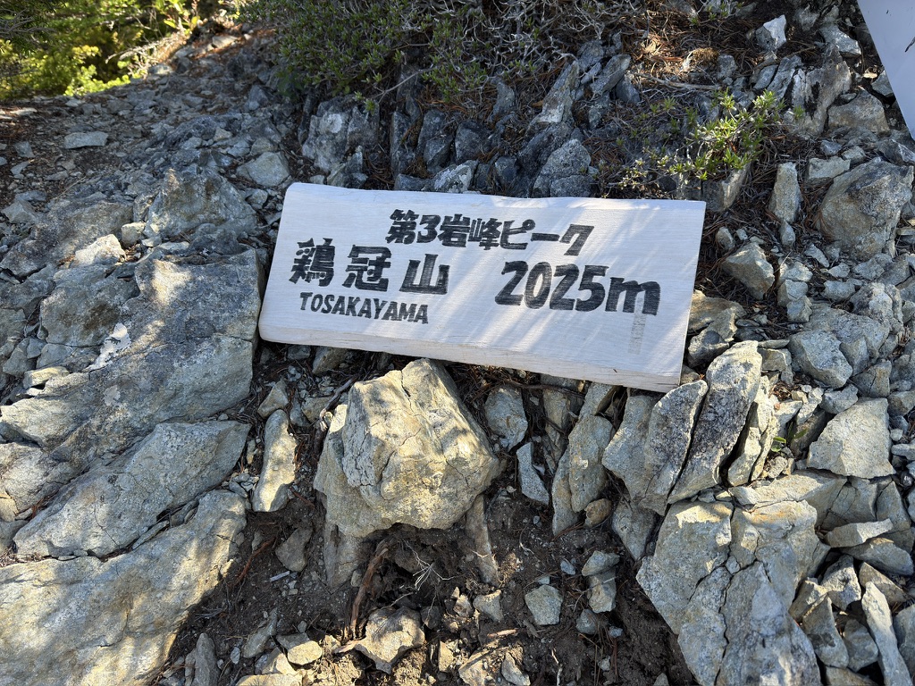 真新しい「第三岩峰ピーク　鶏冠山 2025m」の看板（第三岩峰ピークで撮影）