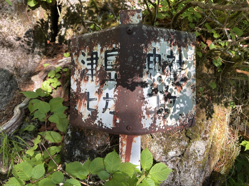 「津島神社 ヒカリゴケ」と書かれた看板。かすれてほぼ見えない