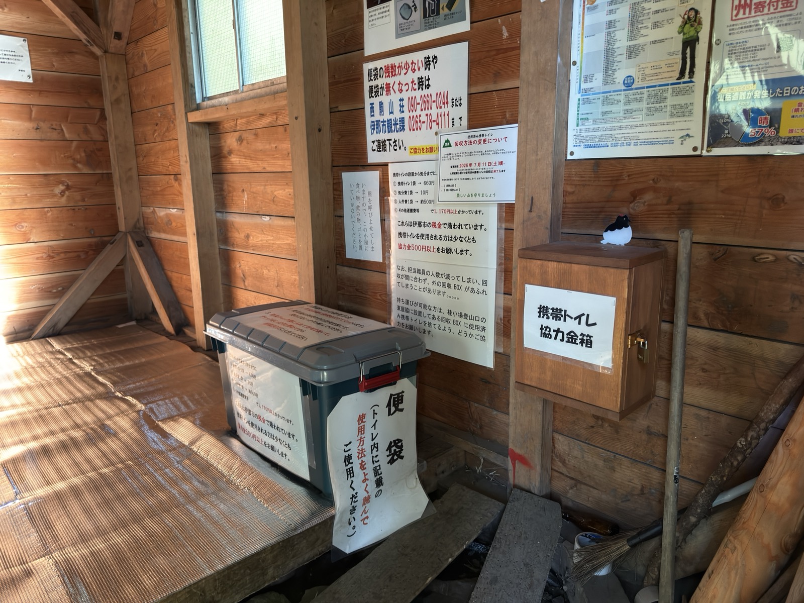 大樽避難小屋の掲示。携帯トイレの協力金箱と便袋の料金表、連絡先