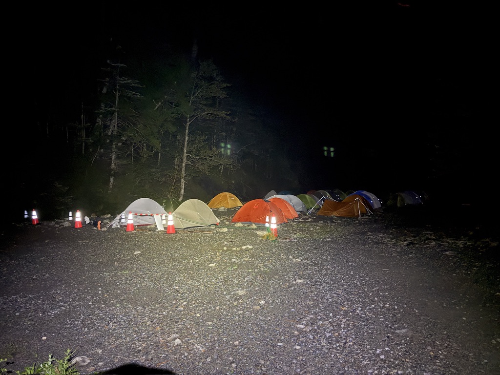 夜のテント場。ライトに照らされたテントが並ぶ