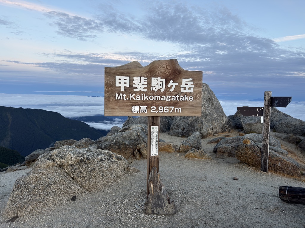 甲斐駒ヶ岳の山頂標識「甲斐駒ヶ岳 Mt.Kaikomagatake 標高2,967m」。奥に雲海