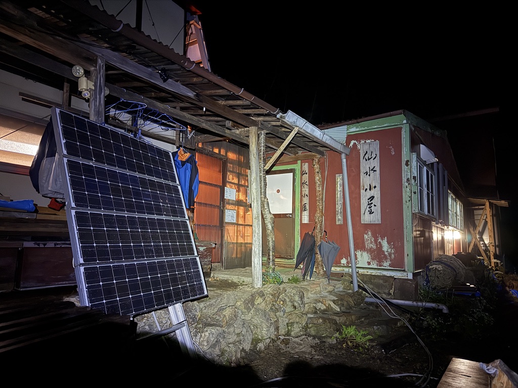 夜の仙水小屋。ソーラーパネルと「仙水小屋」の看板
