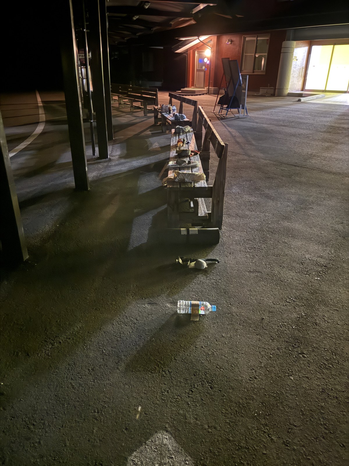 夜の仙流荘前。ベンチの上に一列に並んだペットボトルと荷物