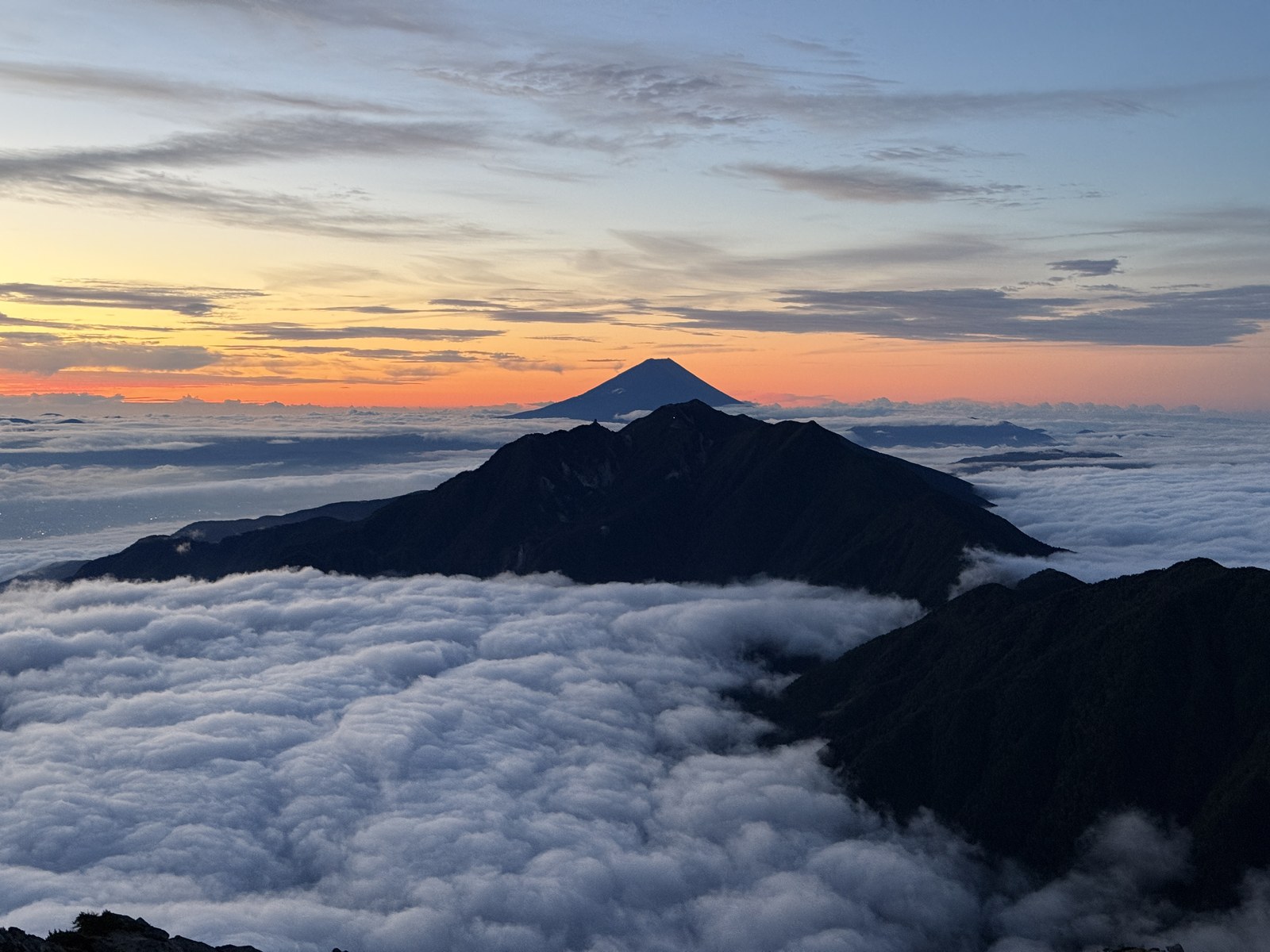 朝焼けの空に浮かぶ富士山と鳳凰三山、一面の雲海