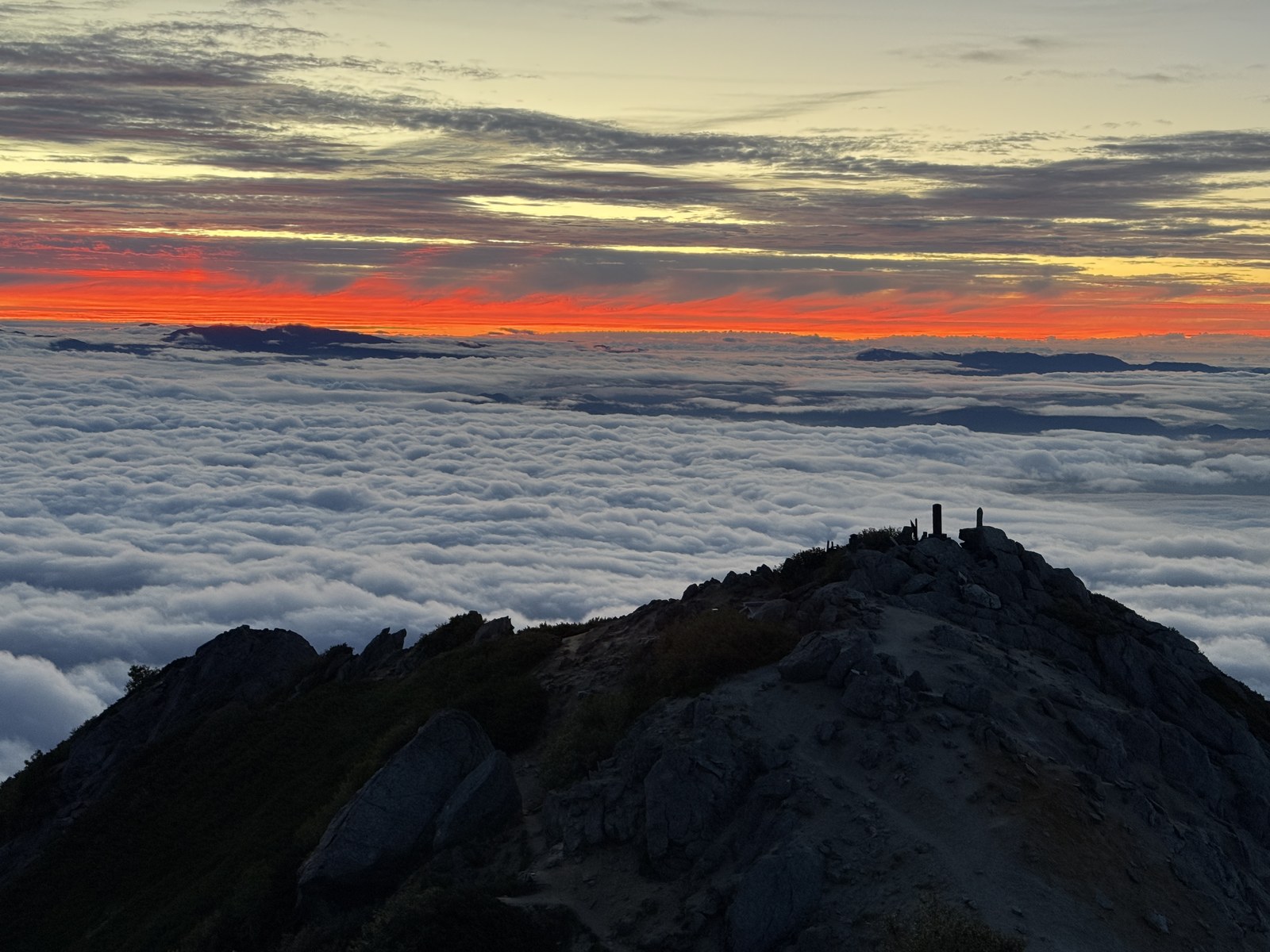 真っ赤に焼けた地平線と一面の雲海、山頂のシルエット