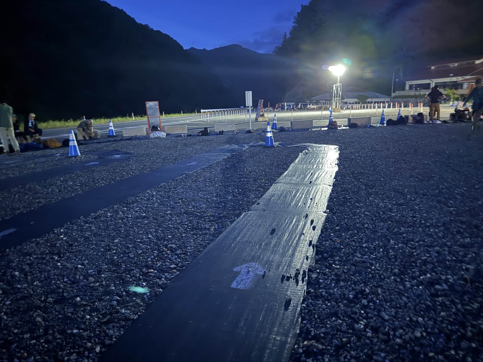 夜明け前の戸台パーク。黒シートのレーンに沿ってザックが一列に並ぶ
