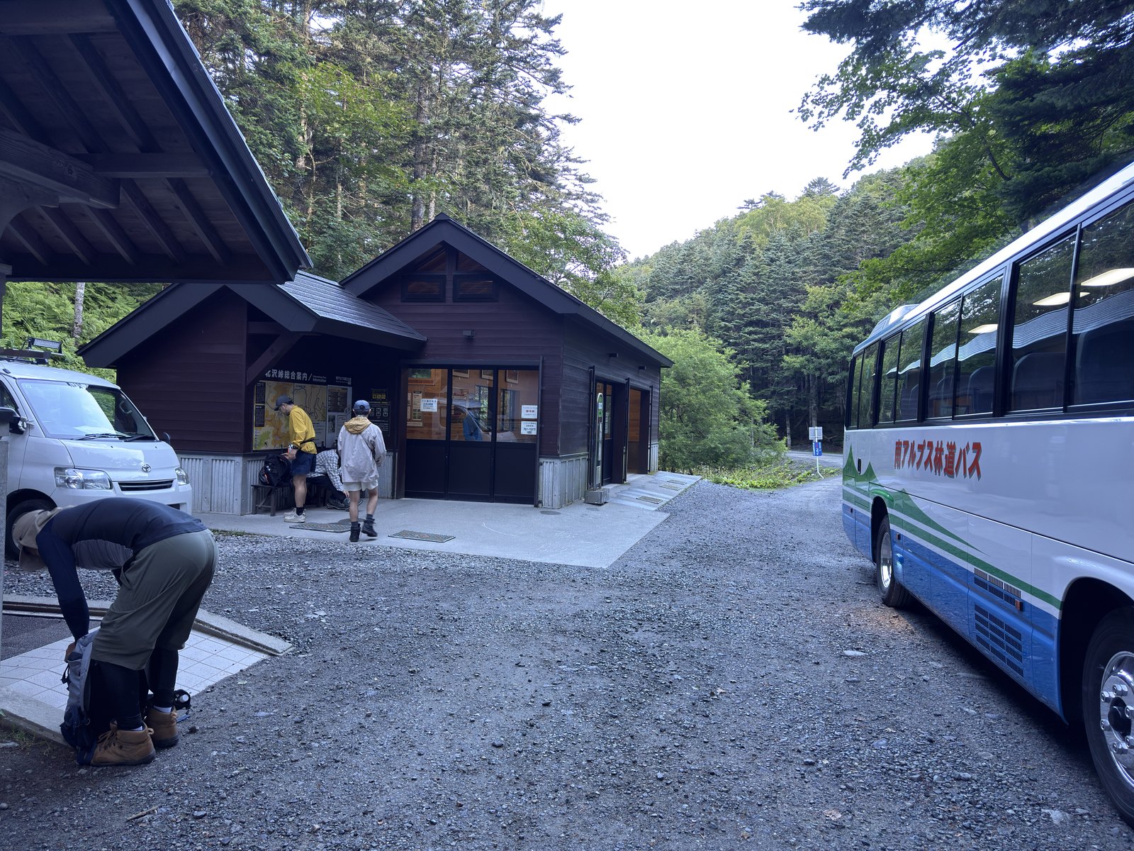 北沢峠のバス降車場。「北沢峠総合案内」の木造の建物と、南アルプス林道バスの車体