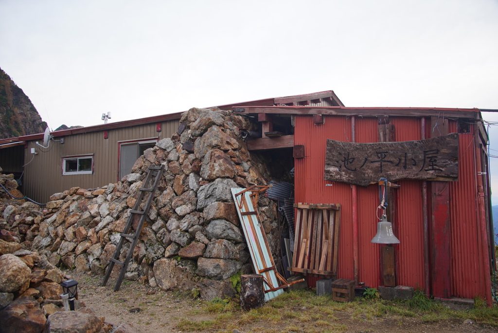 石垣に囲まれた池ノ平小屋と、吊るされた鐘
