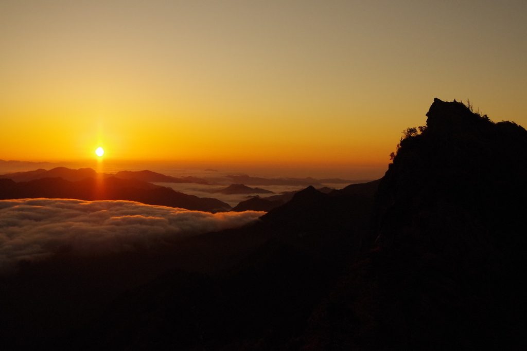 雲海の上に昇る朝日と、山のシルエット