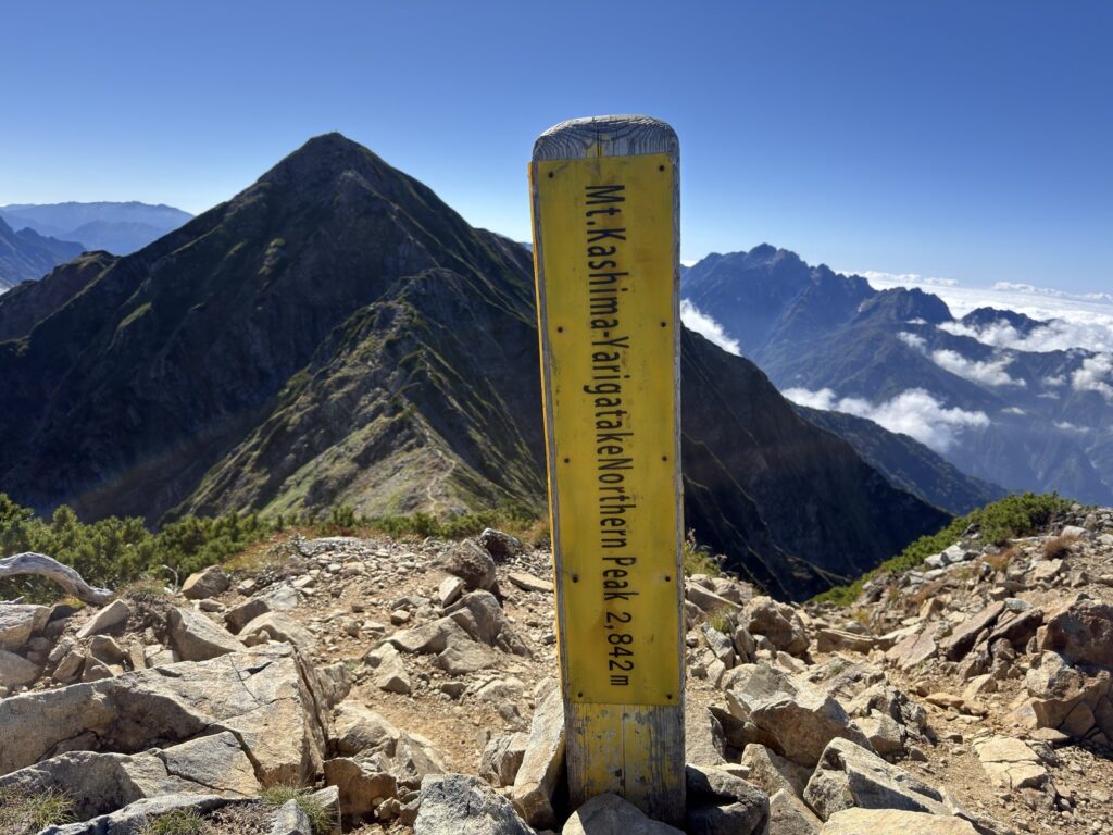 鹿島槍ヶ岳北峰の標柱「Mt.Kashima-Yarigatake Northern Peak 2,842m」と、うしろのとがった南峰
