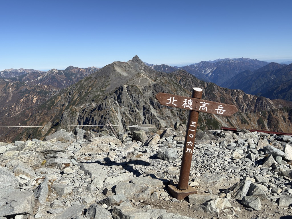 北穂高岳の標柱。奥に槍ヶ岳